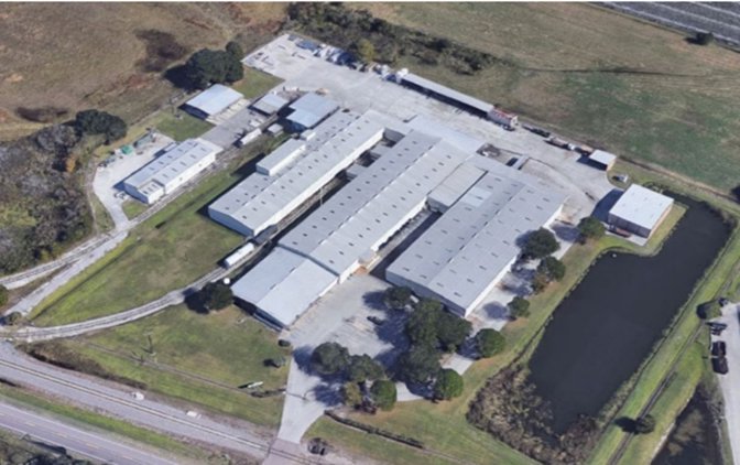 Aerial view of a manufacturing and warehouse site with several large buildings beside a railroad